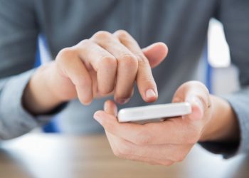 Close-up of male hands holding smartphone and touching screen. Businessman texting message or networking