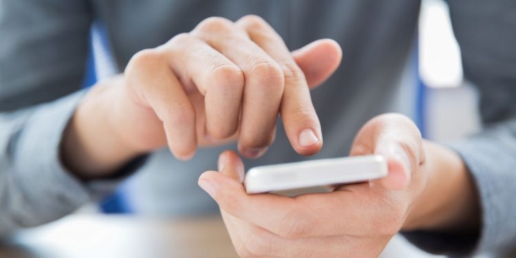 Close-up of male hands holding smartphone and touching screen. Businessman texting message or networking