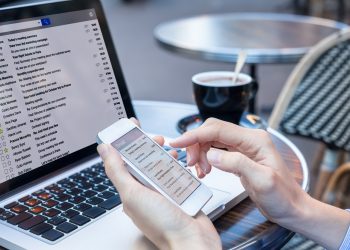 Business person reading emails on smartphone and laptop computer screen online, communication and marketing concept