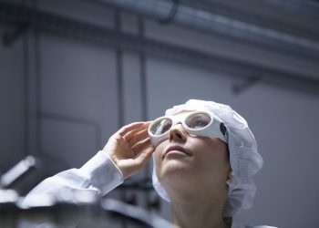 Technician with protective cap and safety glasses looking up in a labroratory