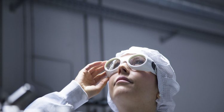Technician with protective cap and safety glasses looking up in a labroratory