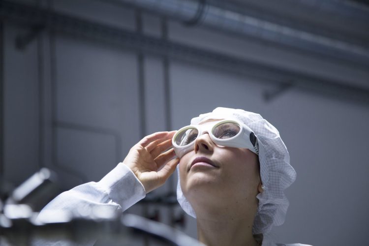Technician with protective cap and safety glasses looking up in a labroratory